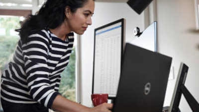 Person standing at a desk with multiple monitors and a laptop