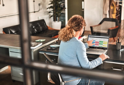 Una persona vista a través de una ventana usa Visio en una portátil.