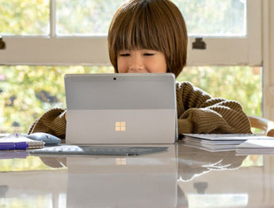 Ein Kind, das an einem Tisch sitzt und ein Tablet nutzt