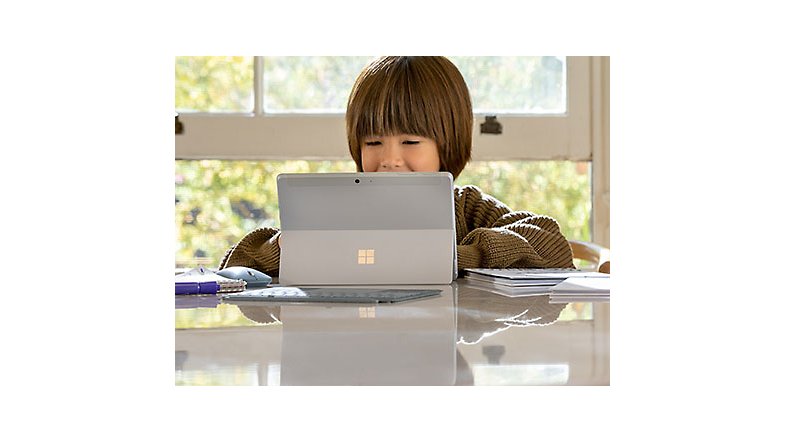 A child sitting at a table using a Surface device