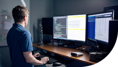 Person som arbetar vid ett skrivbord och tittar på två skärmar