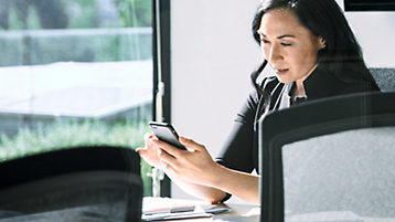 A person sitting at a conference table looking at a mobile phone.