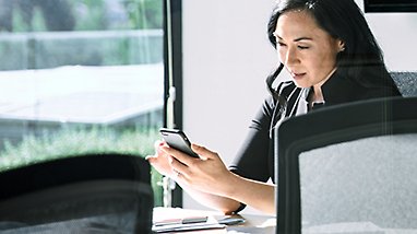 A person sitting at a conference table looking at a mobile phone