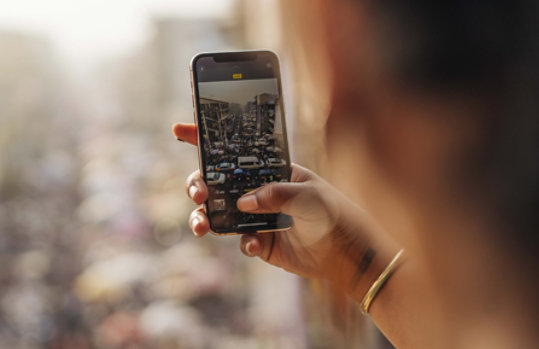 Een persoon die een foto van een drukke straat neemt met een telefoon.