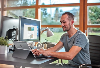 A person working in a home office on a tablet