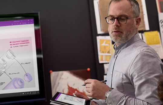 Fotografía de una persona en un espacio de estudio creativo profesional trabajando en una tableta con un lápiz. El proyecto en la tableta también se muestra en un monitor grande. 