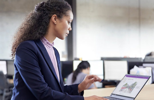 Fotografía de una persona sentada ante una mesa mirando un portátil