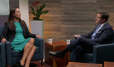 Still image from video showing Alex Bradley and Kelly Joscelyne sitting across from each other having a conversation.