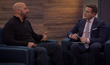 Still image from video showing Alex Bradley and Adam Pisoni sitting across from each other having a conversation.