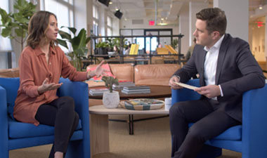 Still image from video showing Alex Bradley and Annie Dean sitting across from each other having a conversation.