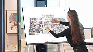 A person with long hair using a Surface Hub to showcase floorplans.