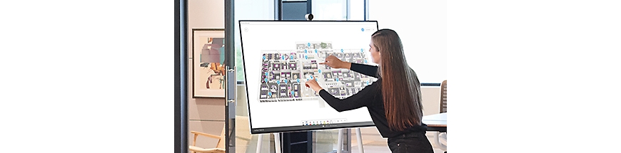 A person with long hair using a Surface Hub to showcase floorplans.
