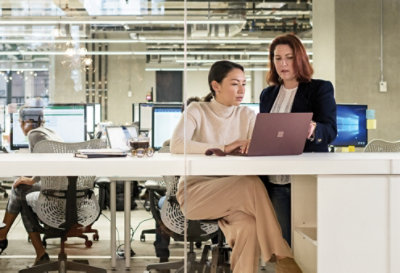 Two people working in an office and conferring over a device