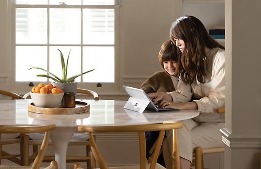 Een volwassene en een kind die samen een tablet gebruiken.