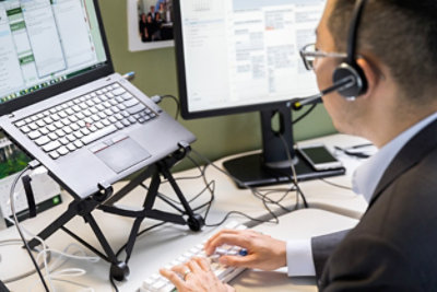 A sales representative wearing a headset and using a laptop.