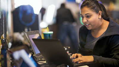 Person som jobber på flere bærbare datamaskiner.