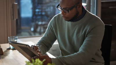Person seated at a table using a stylus to work on a laptop in tablet mode 