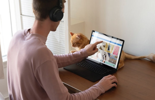 Een persoon die een laptop met touchscreen gebruikt om door foto's in OneDrive te bladeren.