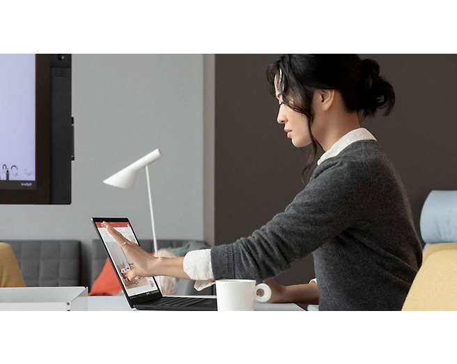 A woman is using a microsoft surface laptop.