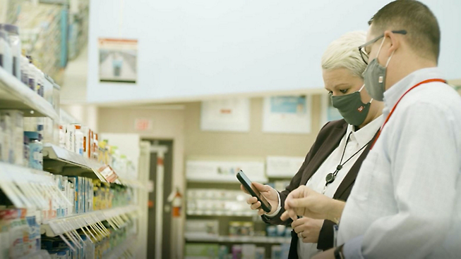 Two people wearing masks in a pharmacy.