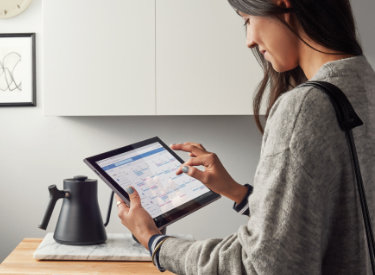 A person looking at a calendar on a tablet while making tea.