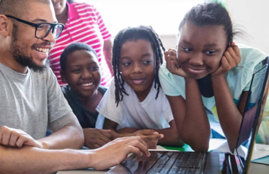 Children with a teacher using a laptop