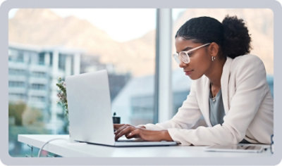 A person in a white jacket typing on a laptop.