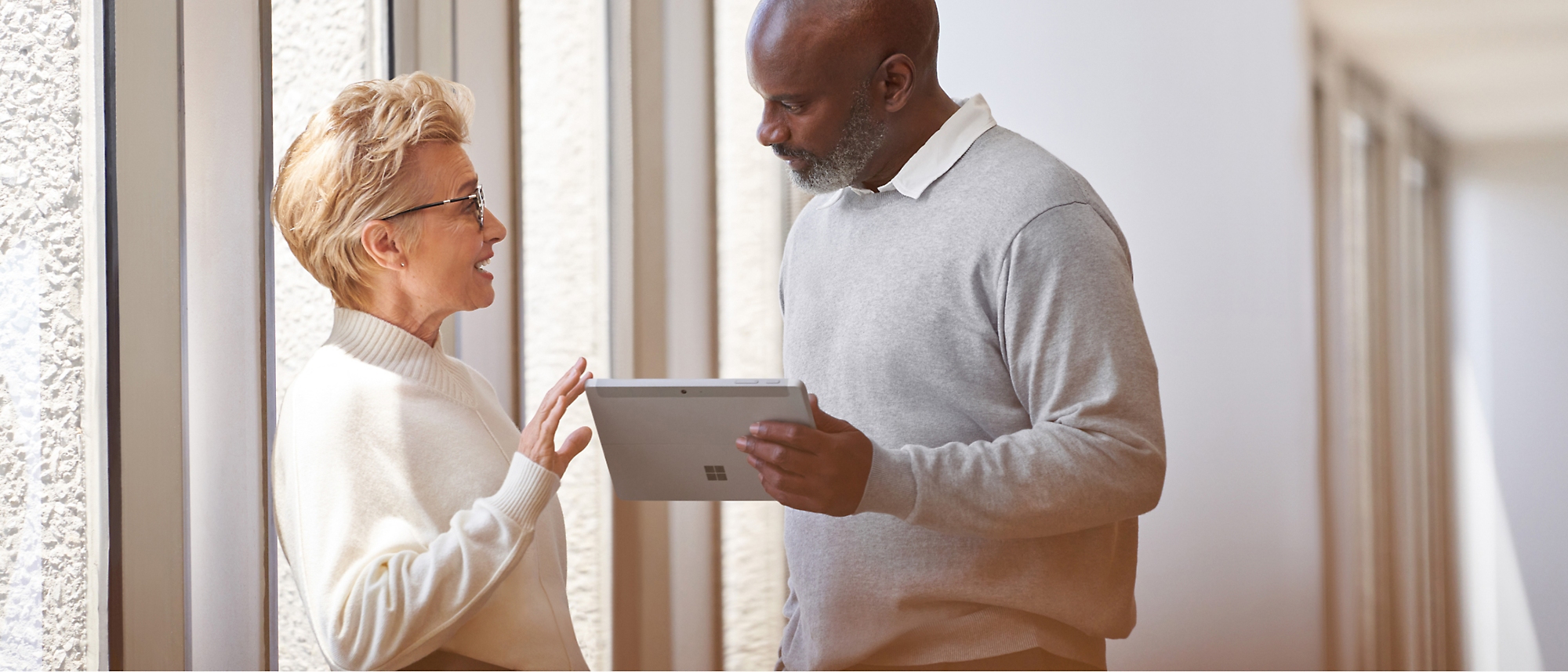 A man and woman standing next to each other holding a tablet.