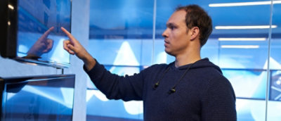A person wearing a blue shirt with a blue background.