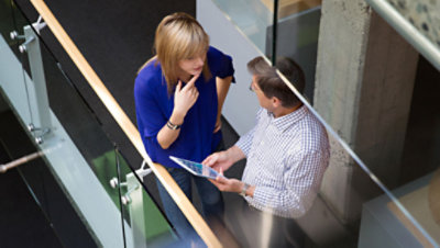 Overhead view of two professionals having a conversation in the hallway of a modern office.