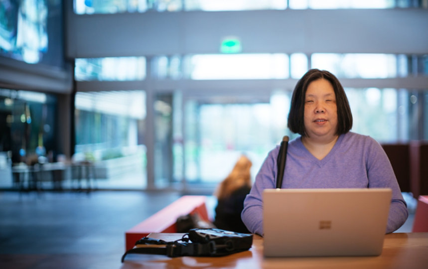 Anne Taylor, who is blind, works on a Surface device with a braille keyboard next to it. 