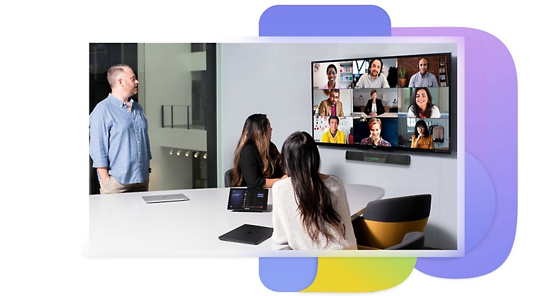 Tres personas en una sala de conferencias mirando a una pantalla montada con nueve personas en una galería de reunión y un dispositivo integrado bajo el monitor.