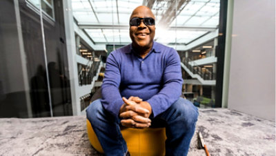 Un homme non-voyant assis sur une chaise et souriant.