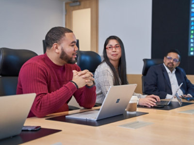A group of people sitting at a table with laptops.
