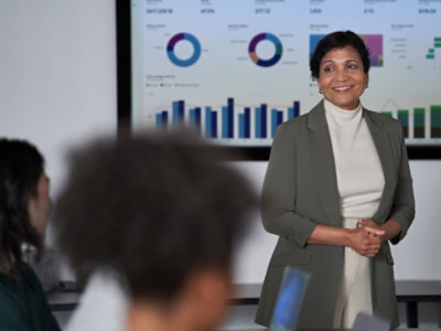 A woman standing in front of a large screen.