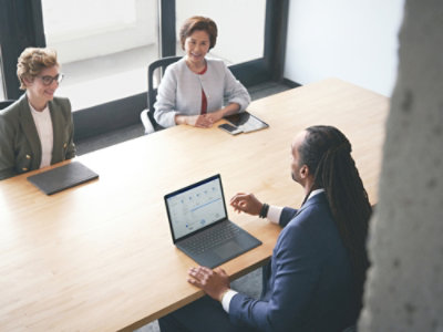 Team meeting around a conference table with a laptop.