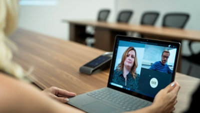 A Teams video call with three participants being displayed on a laptop