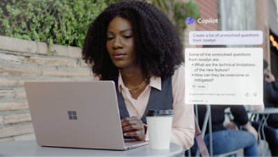 Seorang perempuan sedang duduk di dekat meja dan menggunakan laptop.