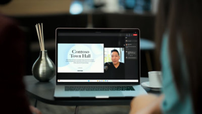 Osoba oglądająca seminarium internetowe „Contoso Town Hall” na laptopie.