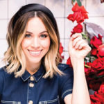 A woman smiling with a bouquet of red flowers.