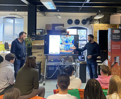 Two individuals presenting in a casual office setting to a seated audience.