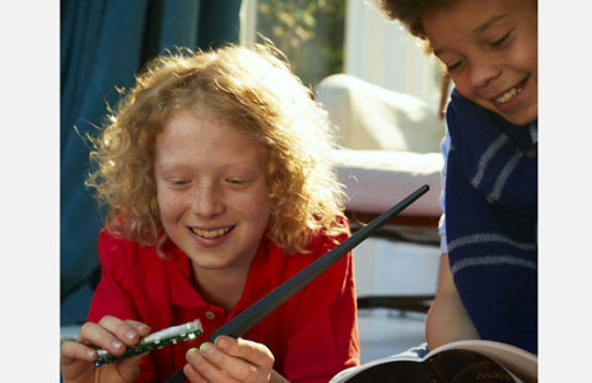 Two kids build the wand that comes with the coding kit.