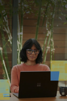 A woman wearing glasses looking at a laptop.