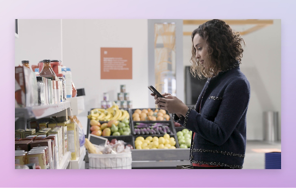 Una chica está de pie en un supermercado usando un teléfono