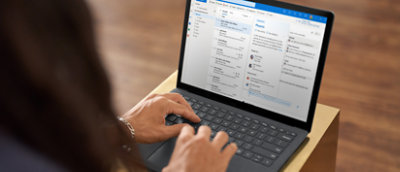 Une femme tapant sur un ordinateur portable sur lequel un e-mail est ouvert.