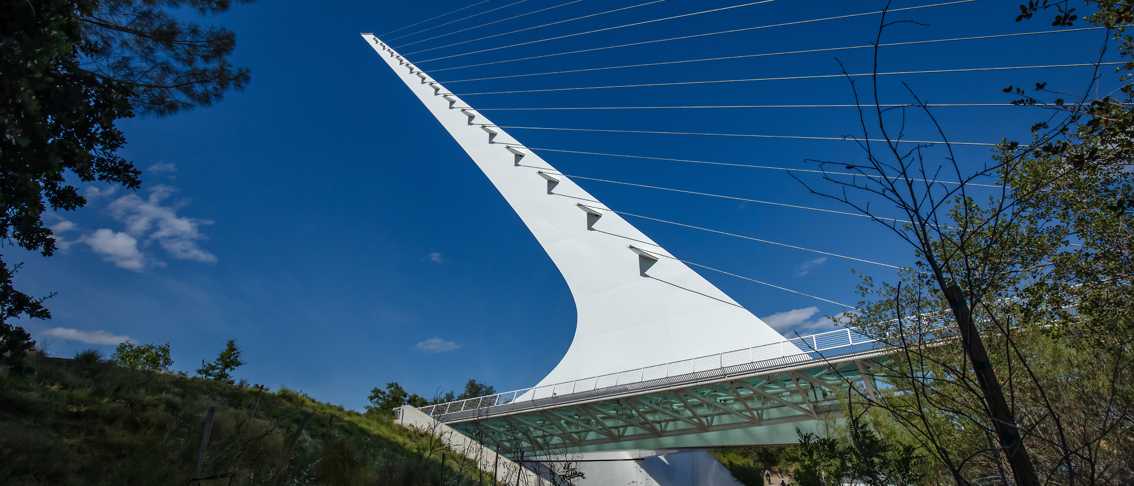 A white bridge with wires with Sundial Bridge at Turtle Bay in the background