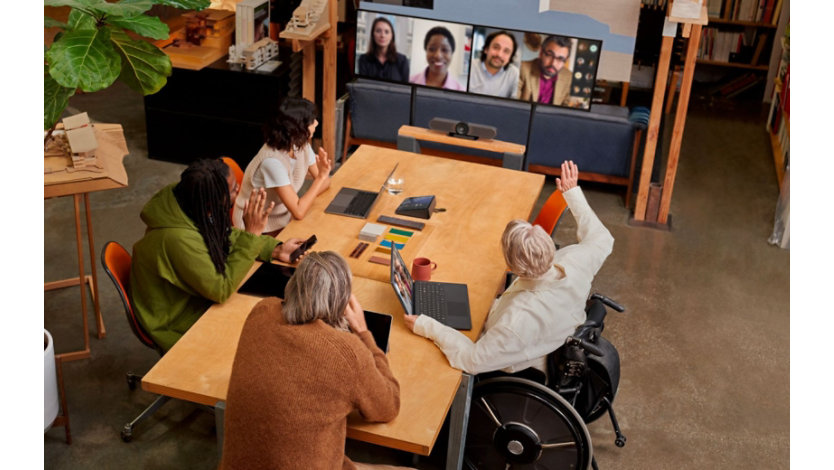 Four people in a conference room participating in a Teams video call being displayed on TVs. 