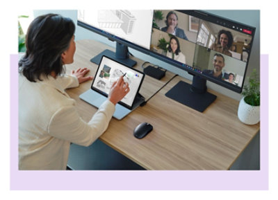 A person sitting at a desk with multiple monitors displaying a Teams video call and architectural designs.
