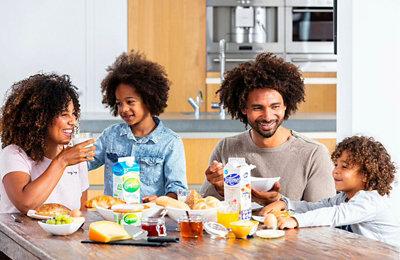 En familie på 4 sitter rundt et bord og spiser frokost.