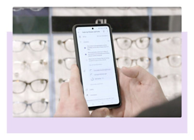 Optiskais veikals un divas rokas, kas tur tālruni, kurā redzama informācija par pasākumu programmā Teams.